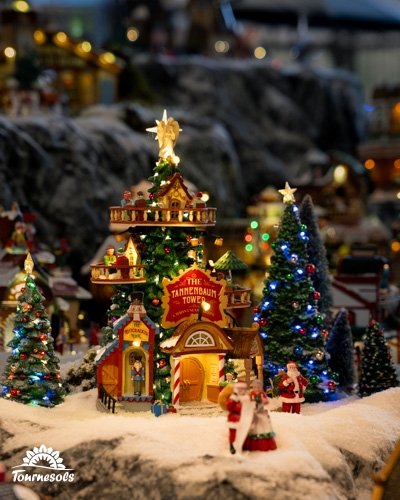 Village miniature Lemax : tour lumineuse en forme de sapin, petits sapins illuminés et figurines dans la neige